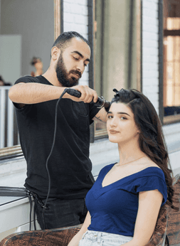 A salon artist is styling customer's hair